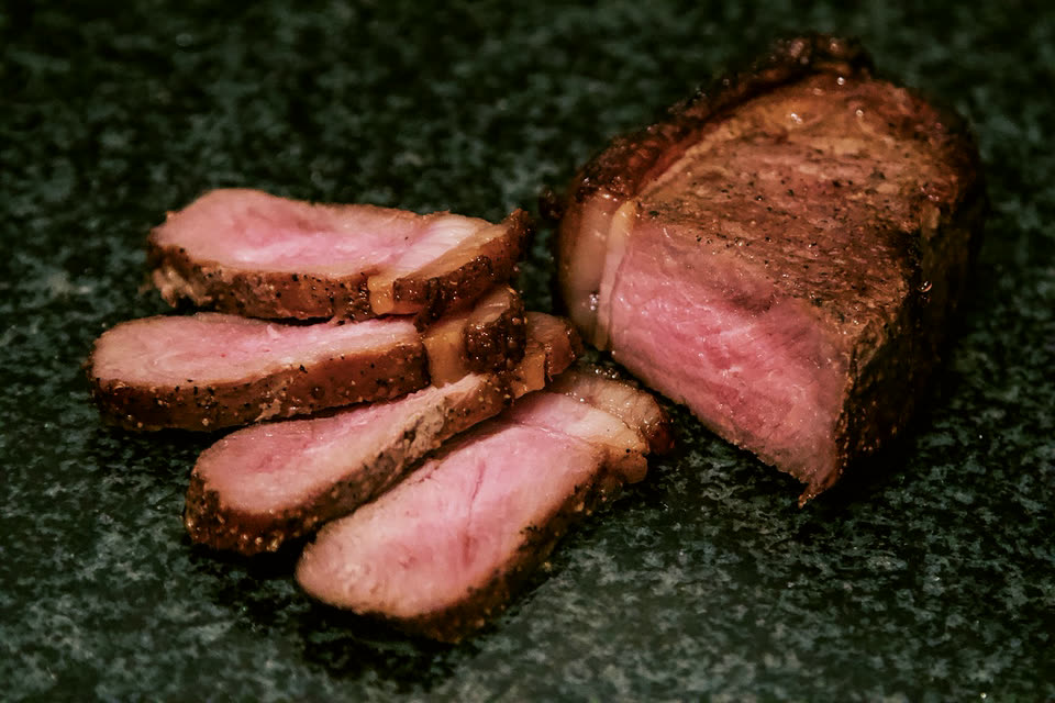 Sliced ribeye, pink in the middle, on dark stone