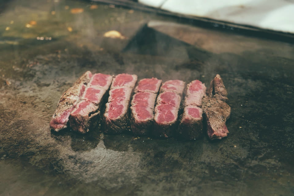 Wagyu slices searing on a flat iron