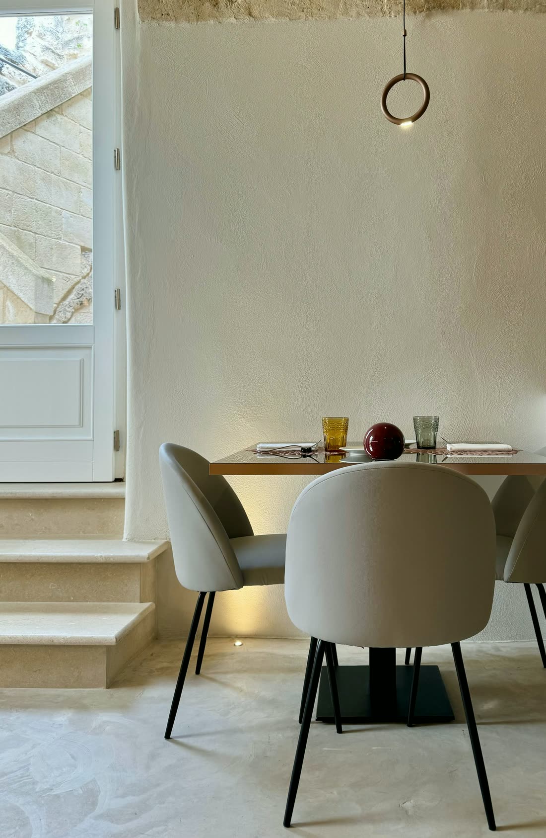 A quiet dining room with stone walls and a single table set for dinner